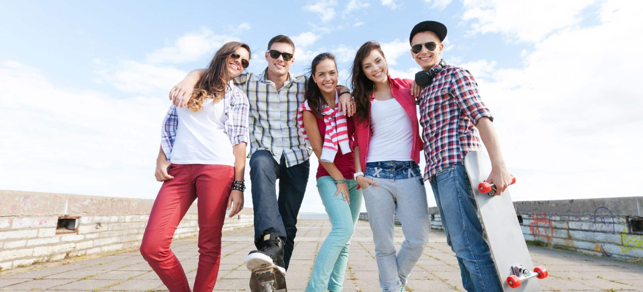 summer holidays and teenage concept - group of teenagers with skates outside