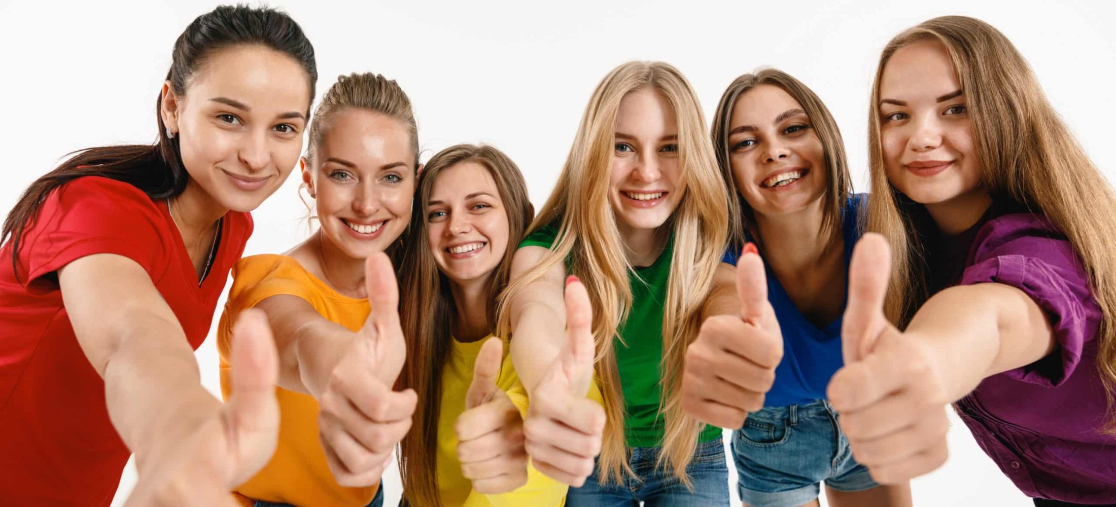 Young women weared in LGBT flag colors isolated on white background. Caucasian female models in bright shirts. Look happy, showing thumbs up. Trust LGBT pride, human rights, freedom of choice concept.